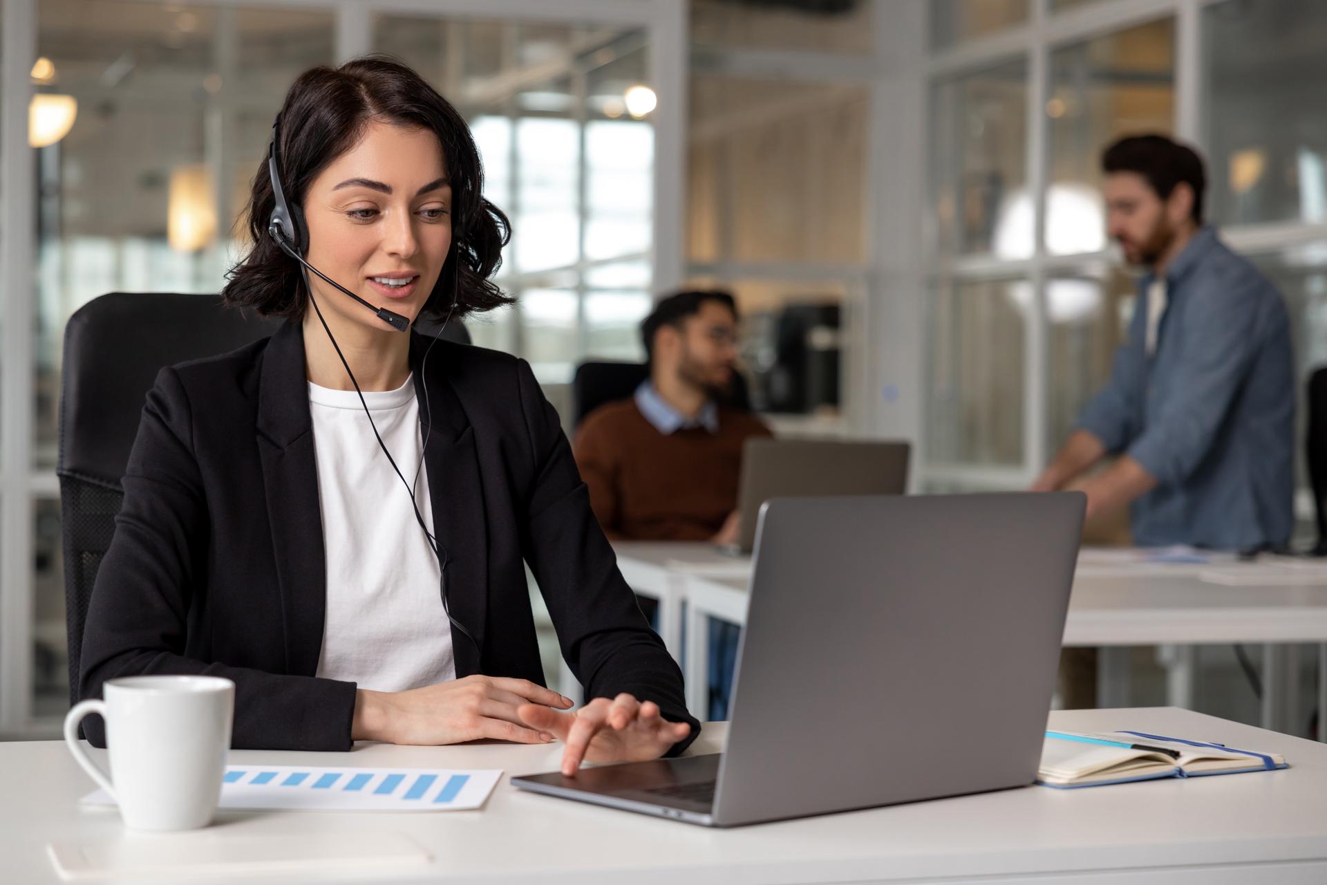 Young friendly operator woman agent with headsets working in call center in contemporary office