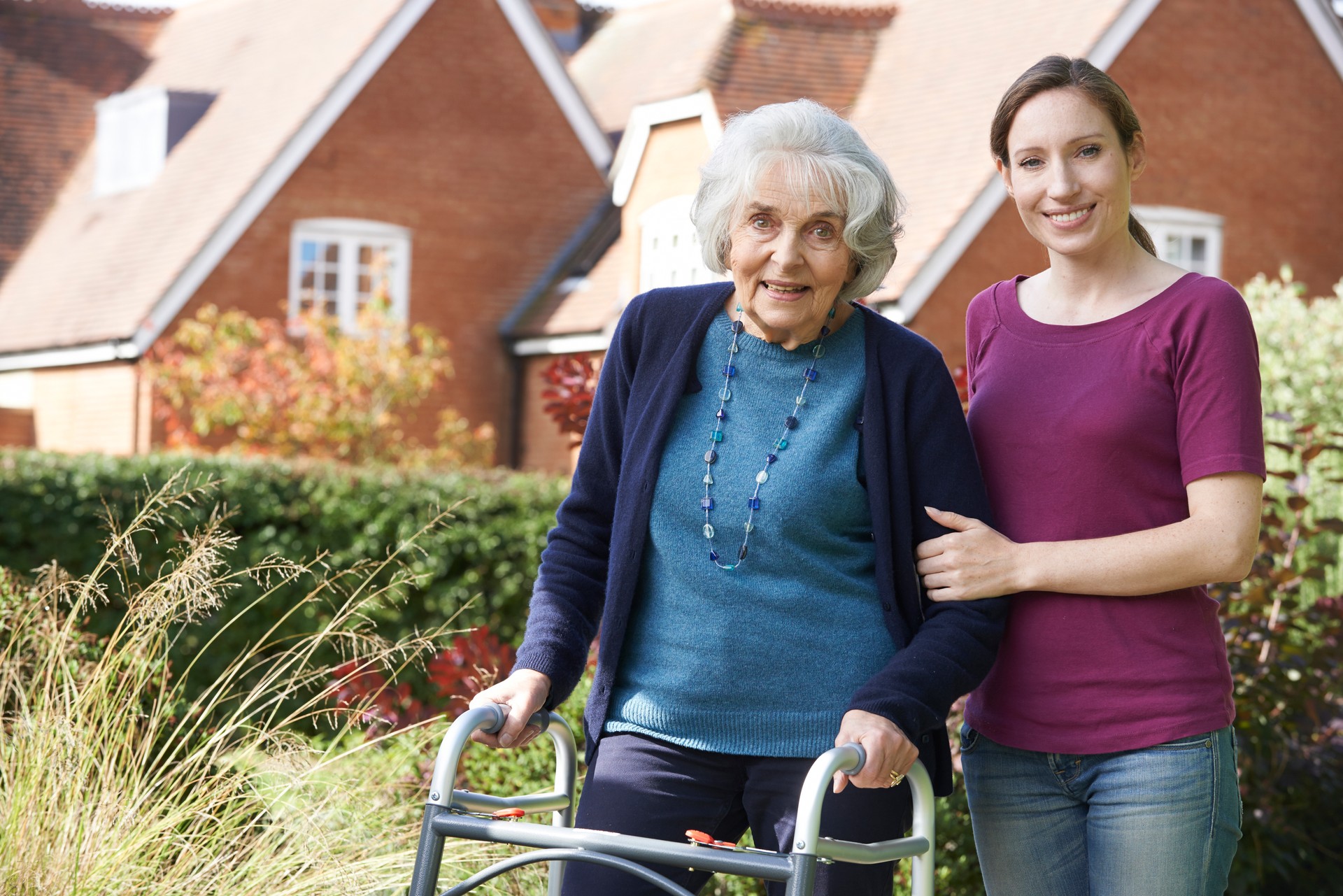 Daughter Helping Senior Mother To Use Walking Frame